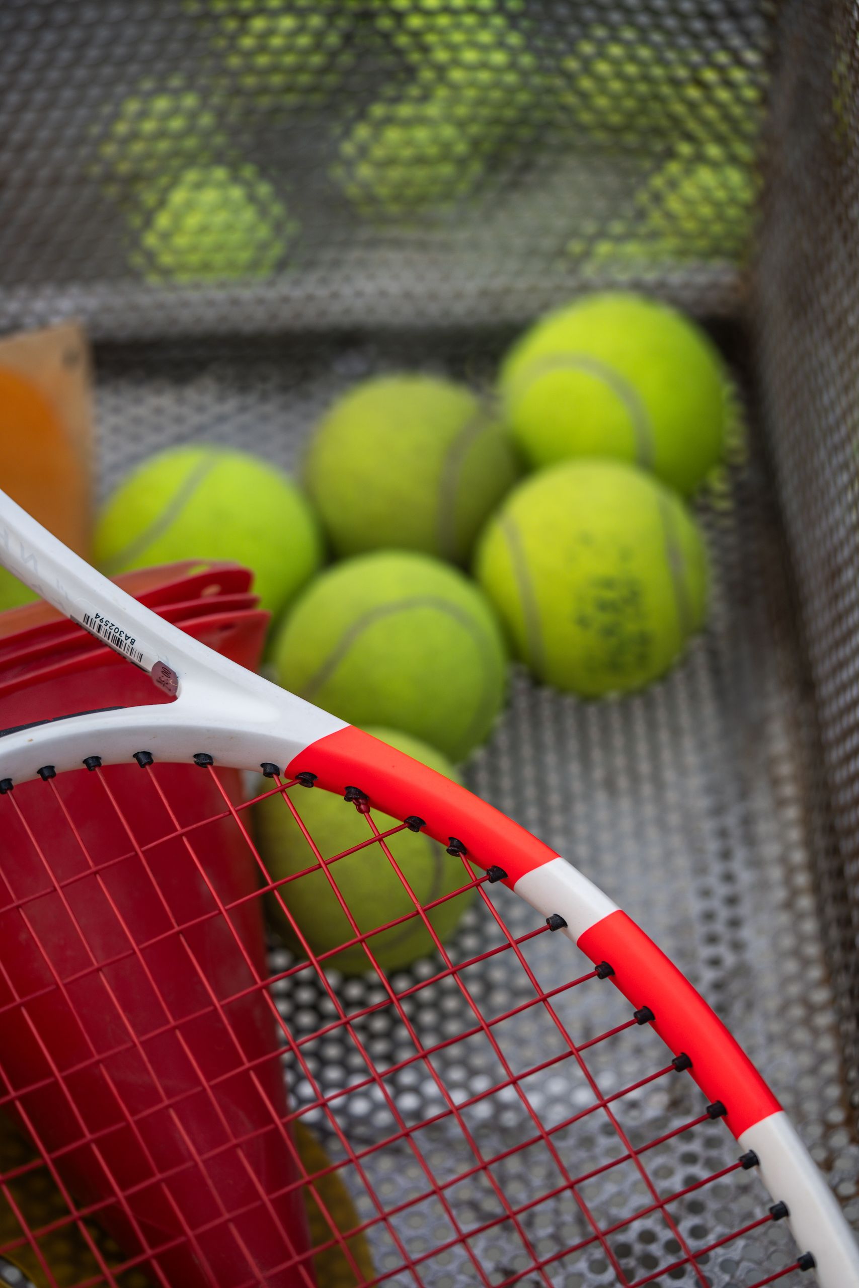 Closeup of tennis racket and balls on court, highlighting vibrant sports gear and practice setup.