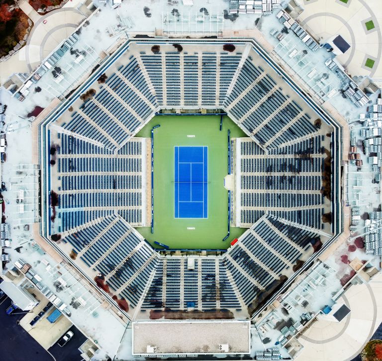 Stunning aerial view of a large, empty tennis stadium with a blue court at the center.