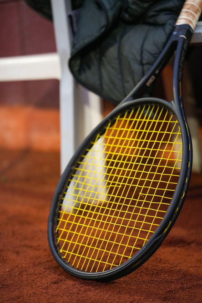 Detailed view of a tennis racket resting on a clay court, ideal for sport-themed projects.