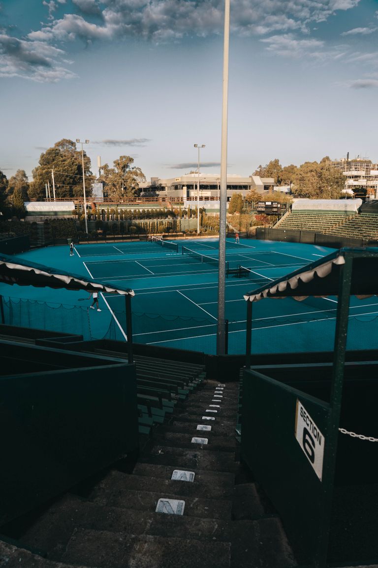 Captivating aerial shot of a tennis court in Melbourne during sunrise, showcasing an urban sports setting.